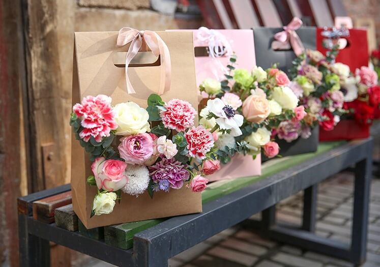 Premium Photo | Bouquet of pink roses in craft paper bag on brown background